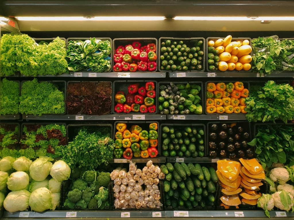 Grocery store shelf lined with bright colorful vegetables